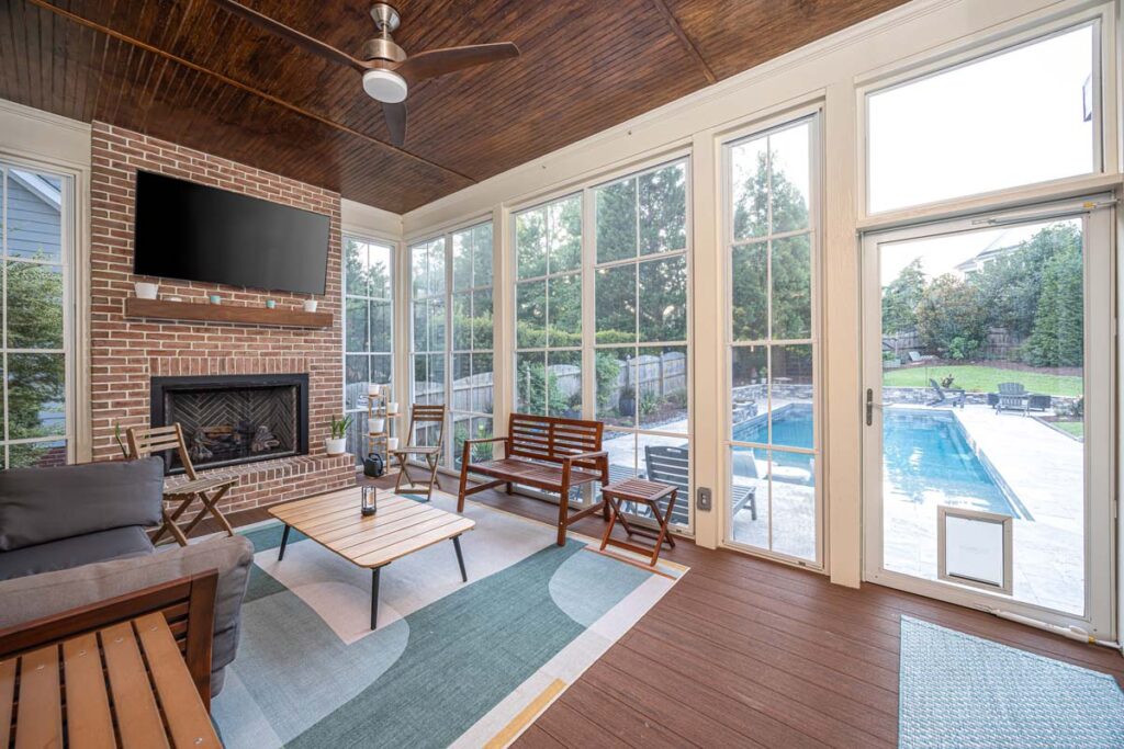 Interior view of Dominion indoor deck with gathering area with fireplace and television, camera looking outdoors.
