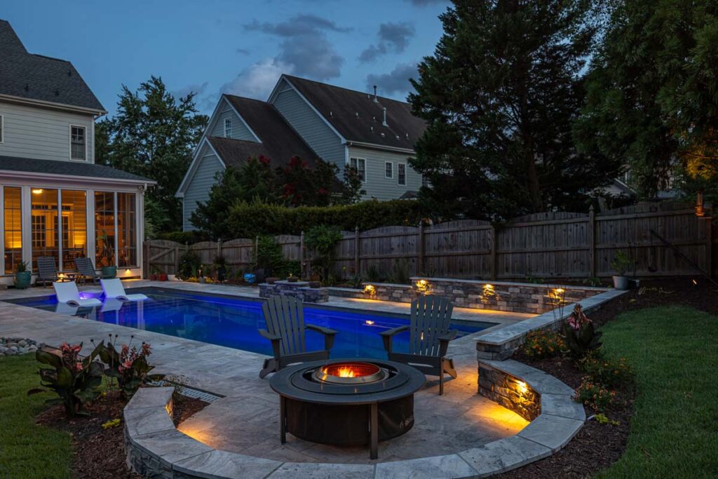 Dominion pool area, deck, fire pit and retaining wall at night.
