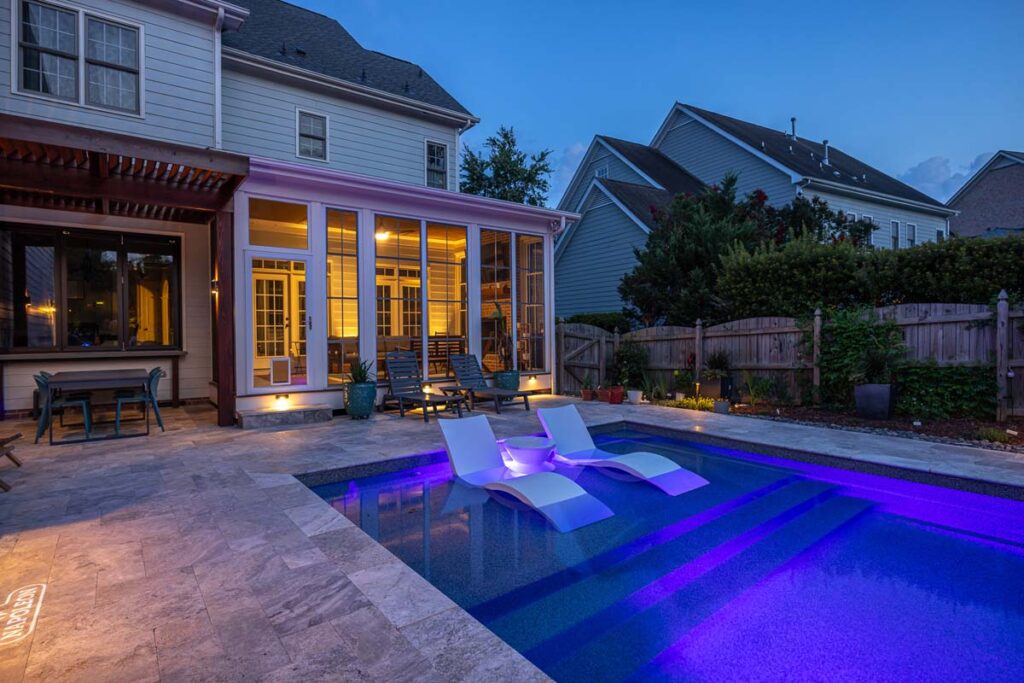 Night view of Dominion pool, indoor deck, pergola and pool, featuring low-voltage lighting and pool lighting.