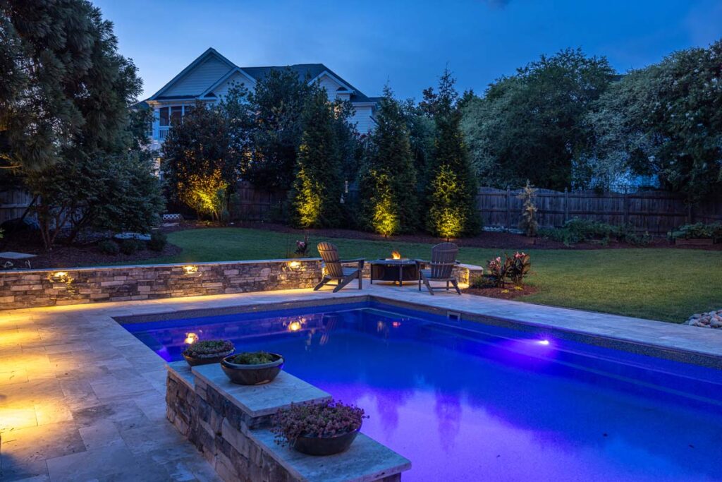 Night view of Dominion project fire pit, and pool showcasing low-voltage lighting.
