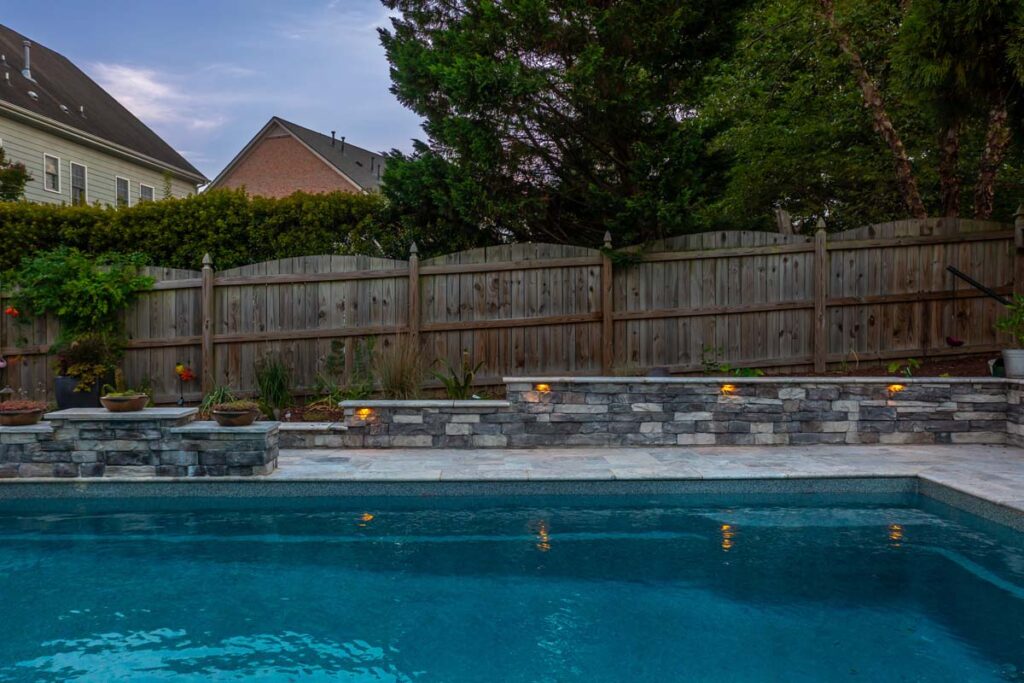 Wide shot drone hovering over Dominion pool, featuring Techo-Bloc patio pavers and surround wall.