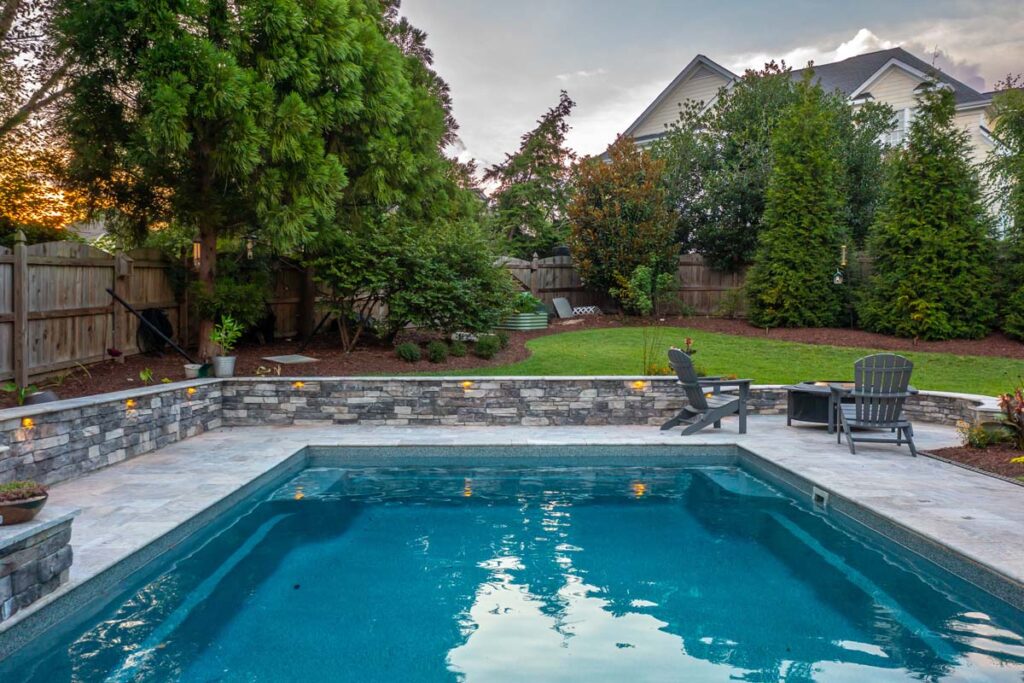 Drone view hovering over Dominion pool with custom surround wall and fire pit.