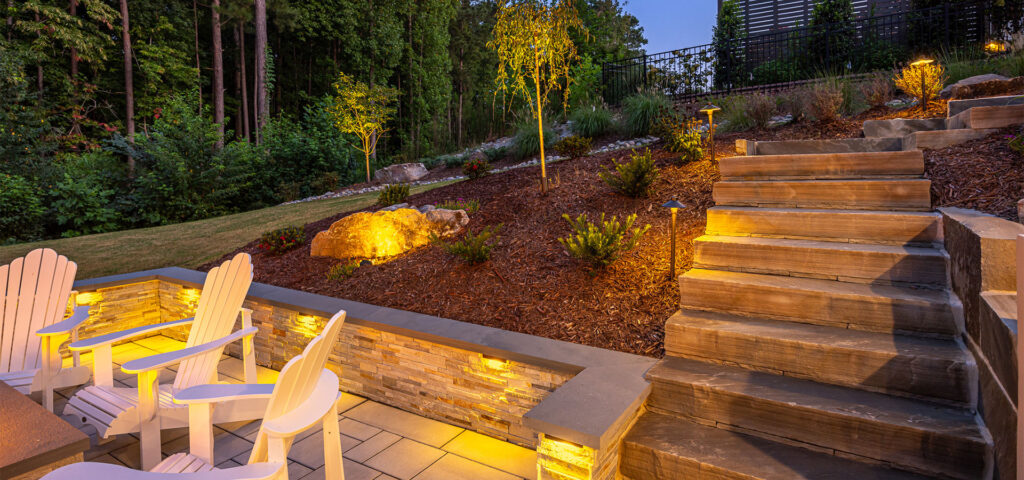 Front view of Roseroot retaining wall and low-voltage lighting. Patio featuring Techo-Bloc pavers are shown are the left and steps are on the right.